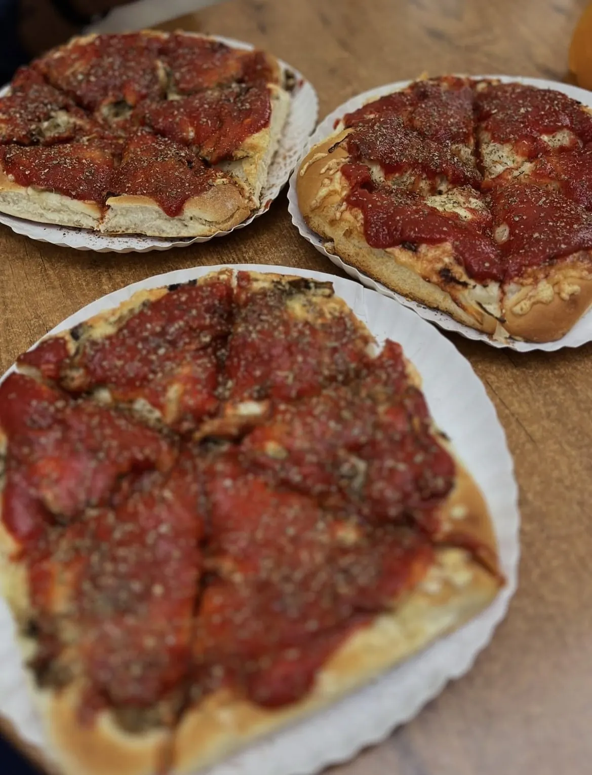 Trzy drożdżowe pizze z Gdynianki na papierowych talerzach